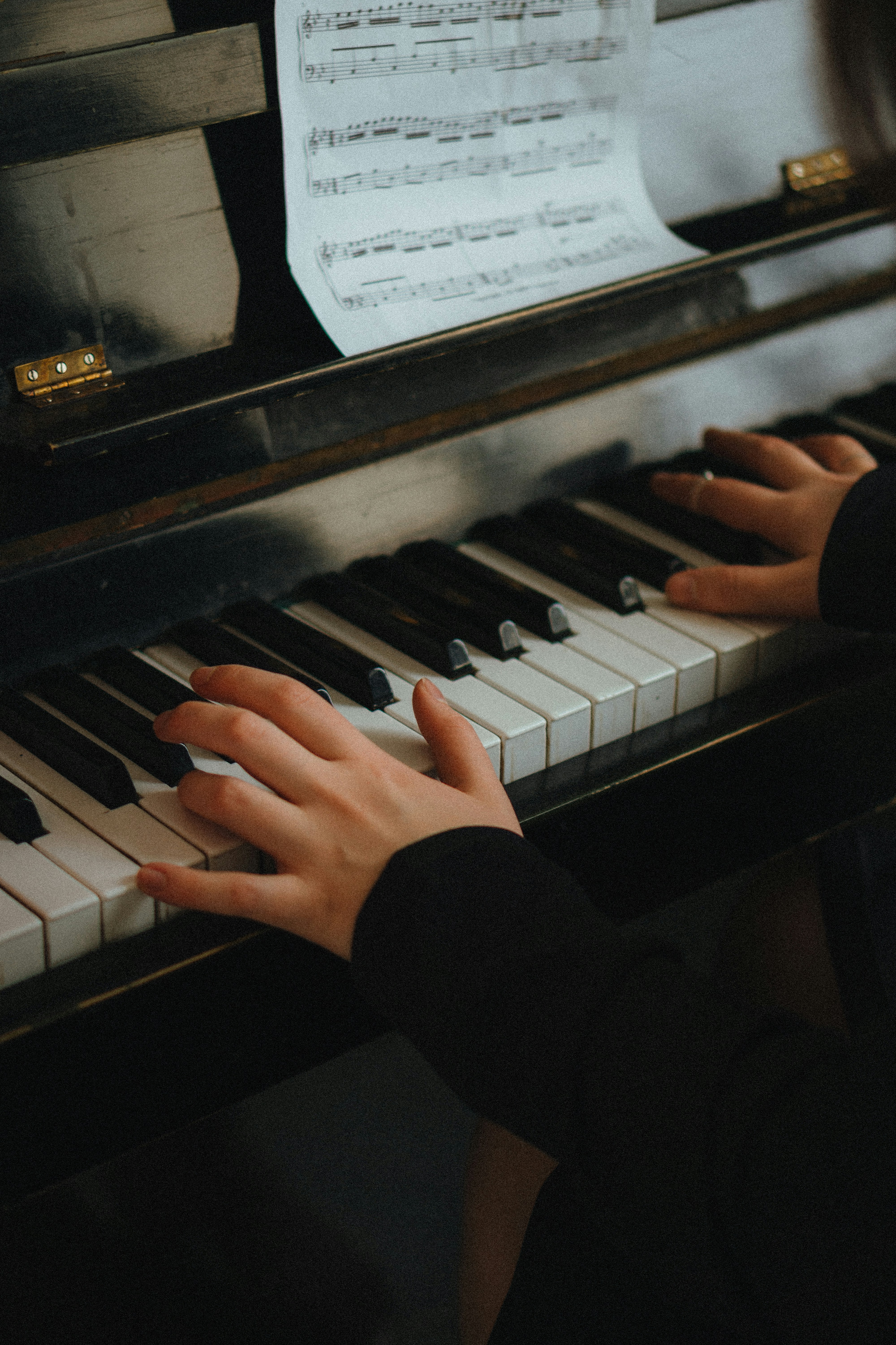 Mãos a tocar piano, com partitura ao fundo